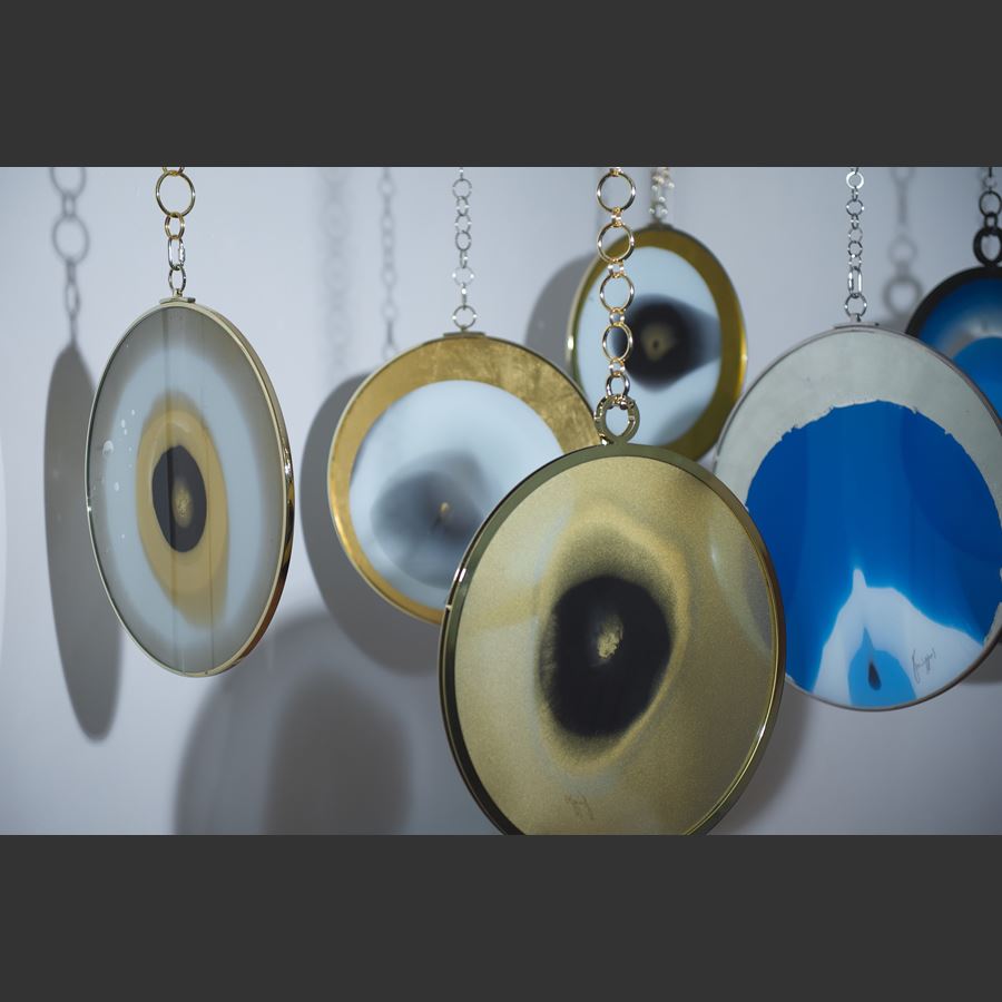 white and gold round art glass sculpture with faint resemblance to an eye on gold chain