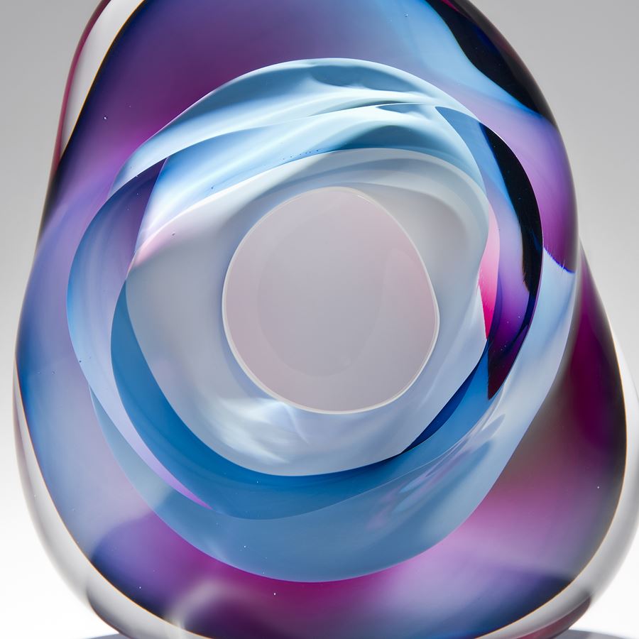 modern art glass sculpture in turquoise blue pink and purple with hole in centre