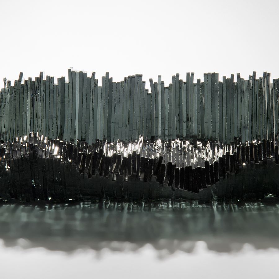 modern art-glass sculpture with hundreds of long thin dark grey shards arranged around edge to form bowl 
