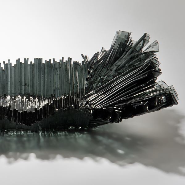 modern art-glass sculpture with hundreds of long thin dark grey shards arranged around edge to form bowl 