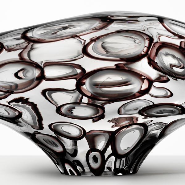 abstract brain-shaped clear glass sculpture with bubble-shaped patterns throughout 
