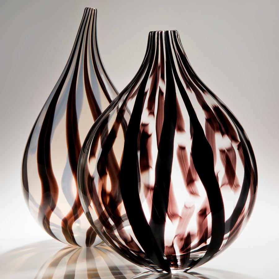 sculpted glass vessel with round base and short neck with black and dark red lined patterns