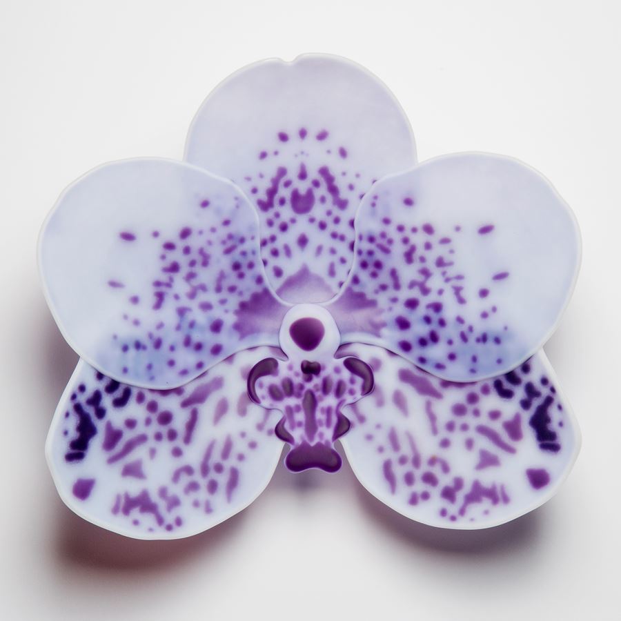 glass artwork of an exotic flower in white with purple speckles