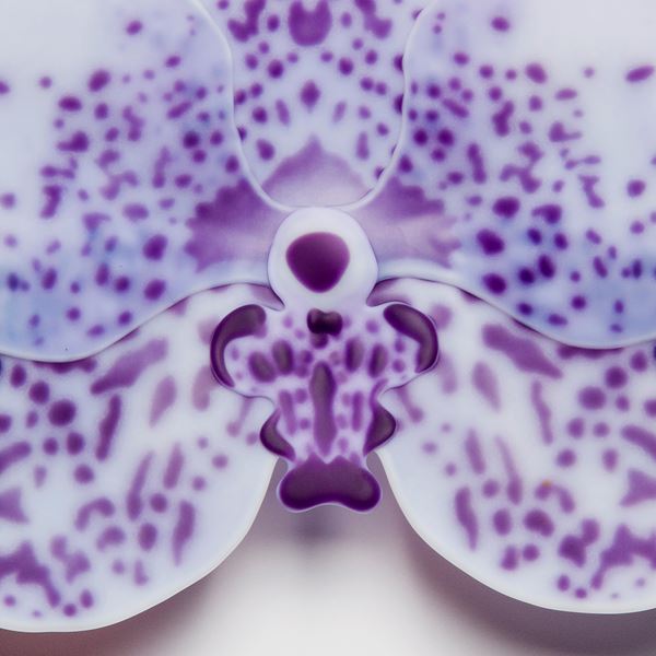glass artwork of an exotic flower in white with purple speckles