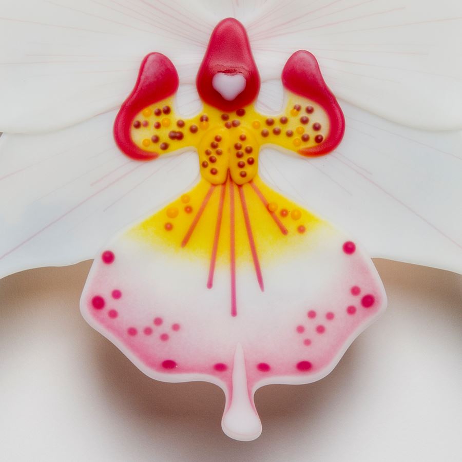 sculpted glass art of a white exotic flower with pink and yellow detail
