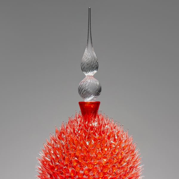 glass sculpture of spiked orange ball in the centre of clear glass base and top