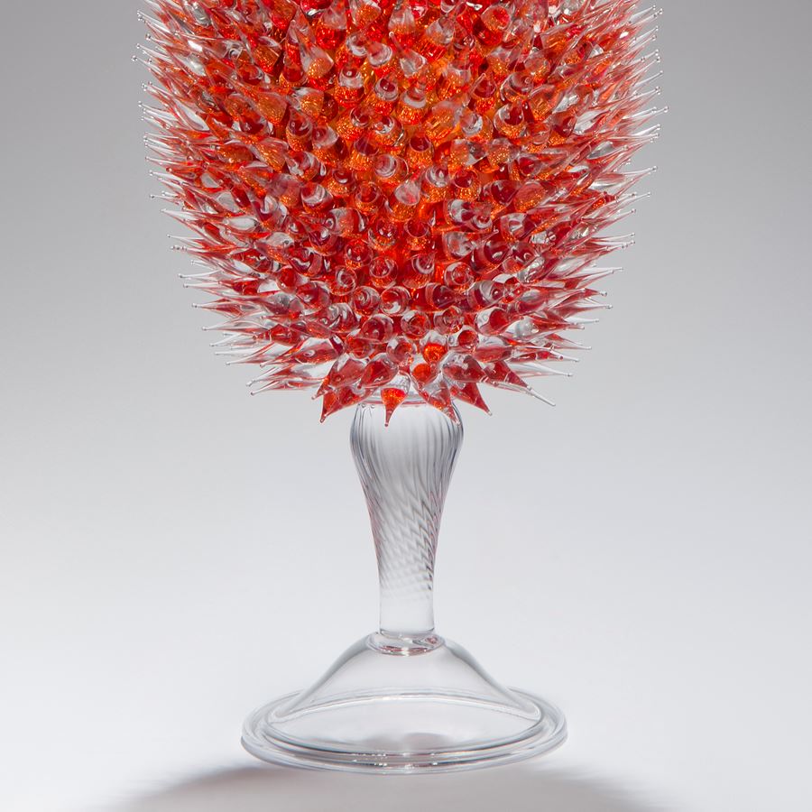 glass sculpture of spiked cherry red ball in the centre of clear glass base and top