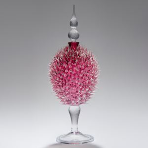 glass sculpture of spiked ruby red ball in the centre of clear glass base and top