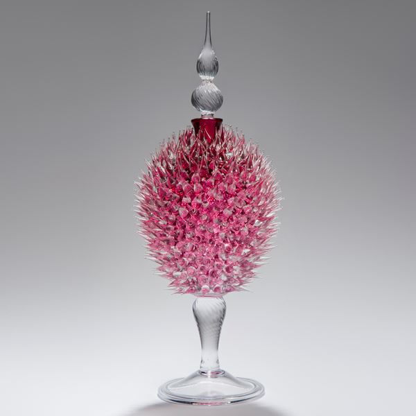 glass sculpture of spiked ruby red ball in the centre of clear glass base and top