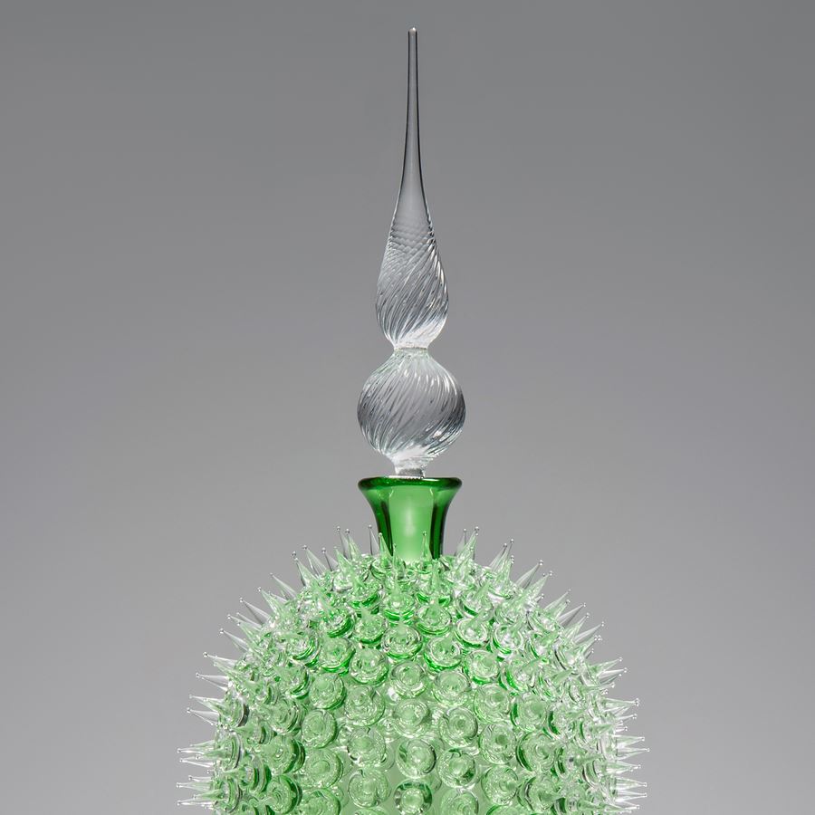glass sculpture of spiked neon green ball in the centre of clear glass base and top