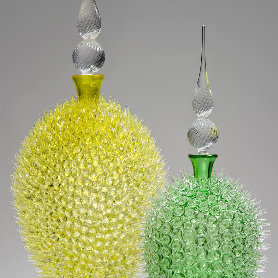 glass sculpture of spiked neon green ball in the centre of clear glass base and top