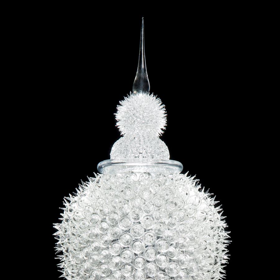 tall white glass sculpture of rounded prickly blobs on long cone with pointed top