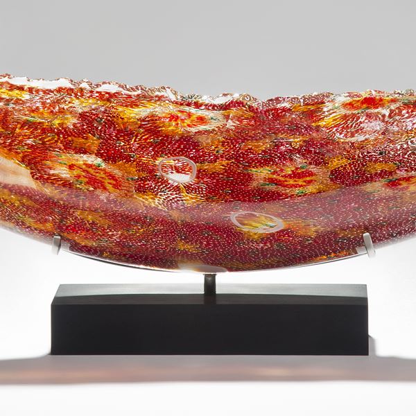 solid glass art sculpture in concave shape with detailled patterns in red and yellow