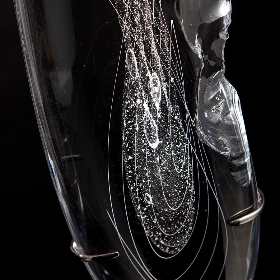 tall thin black art glass sculpture in the shape of a feather with hand chipped exterior patterns
