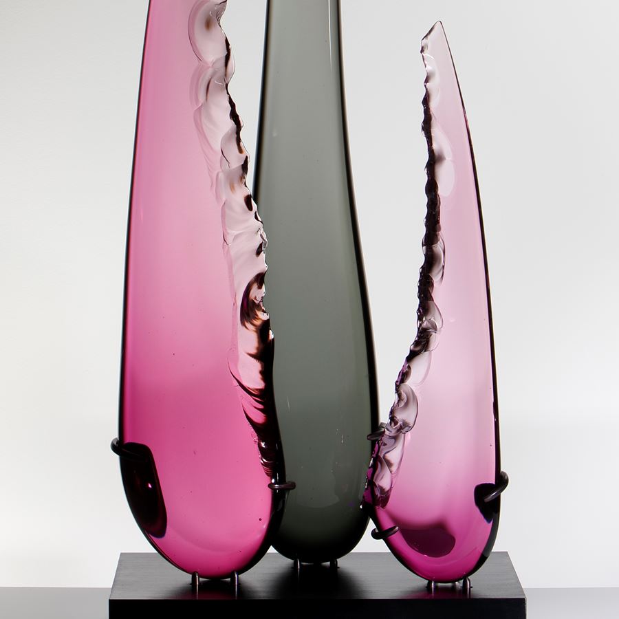 abstract sculpted glass artwork of three long glass shards one long black in the centre and two shorter in purple to either side