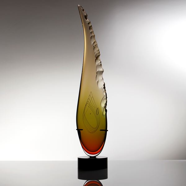 sculpted amber glass in upright feather shape resting on black base