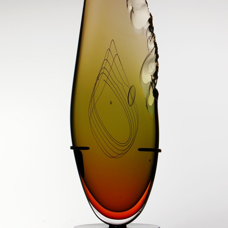 sculpted amber glass in upright feather shape resting on black base