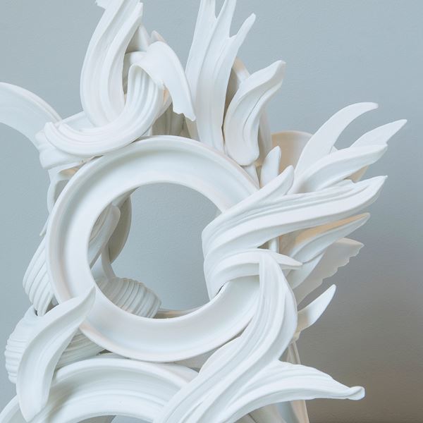 white porcelain sculpture in classical style of arcs and flares intertwined