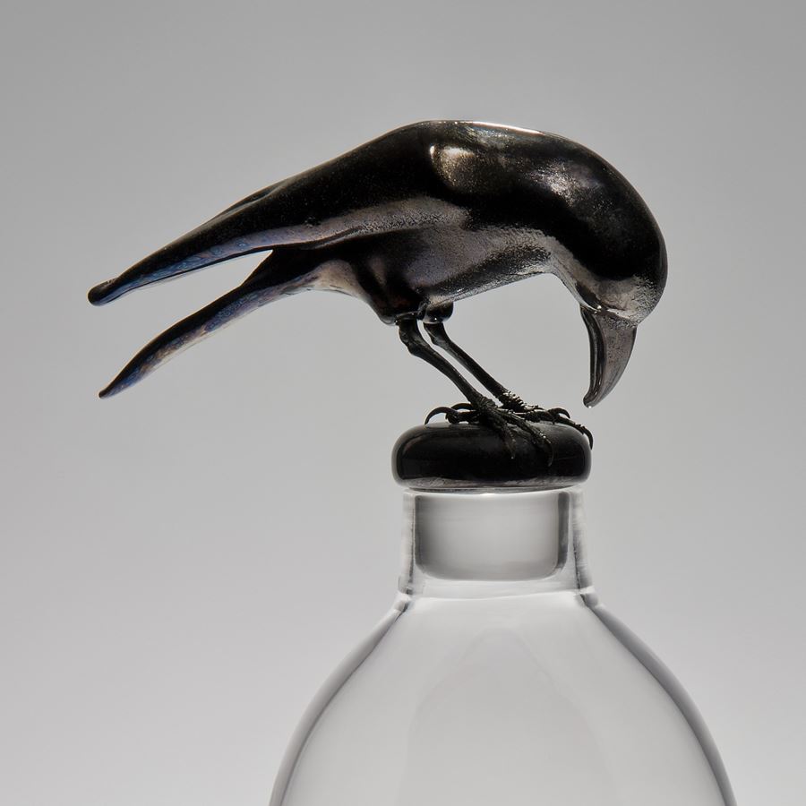 glass and steel sculpture of three apples inside glass container with a crow peering on top looking in