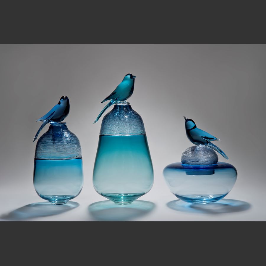 blue glass sculpture of funeral urn with bird on top