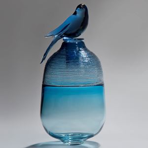 blue glass sculpture of bird sat on top of a funeral urn
