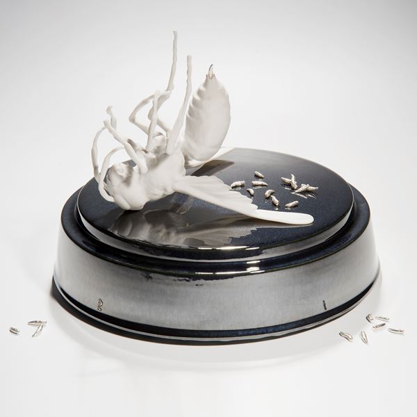 ceramic and metal sculpture of bird and maggots on round base