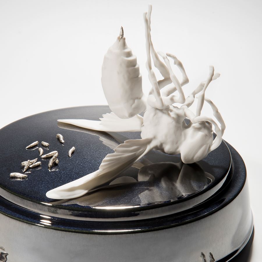 ceramic and metal sculpture of bird and maggots on round base