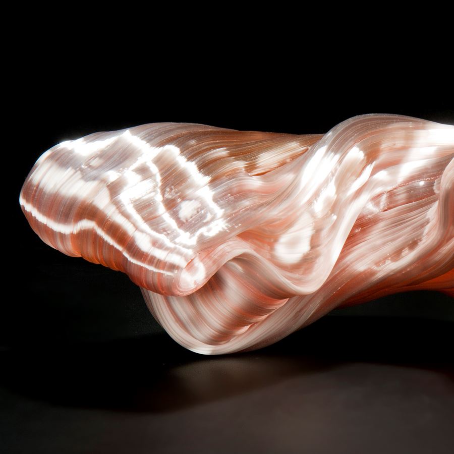 stretched and bent glass formation of abstract sculpture in pink and coral