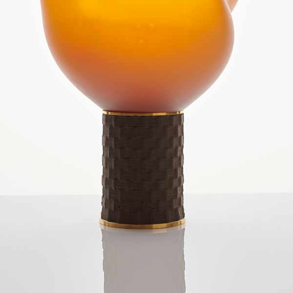 abstract yellow and orange blown flame-shaped glass ornament resting on bronze base