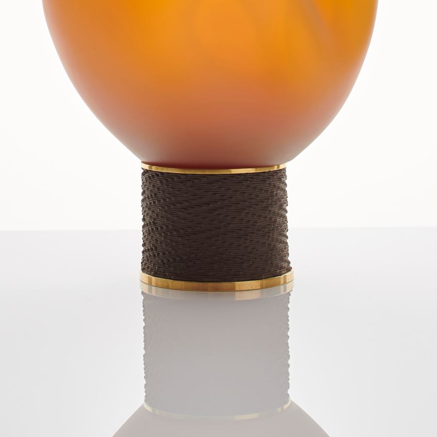 orange modern glass art sculpture of blob shape from blown glass resting on bronze base