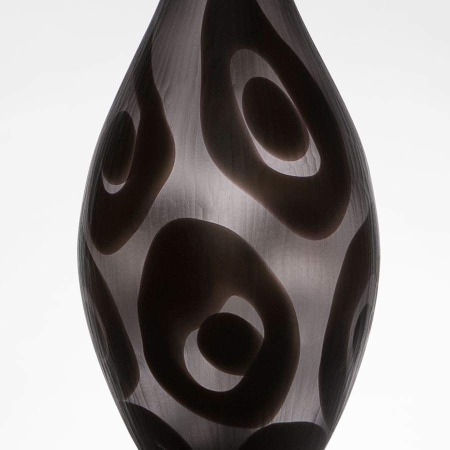 modern tall glass vessel sculpture with thin neck in dark grey and black circle patterns