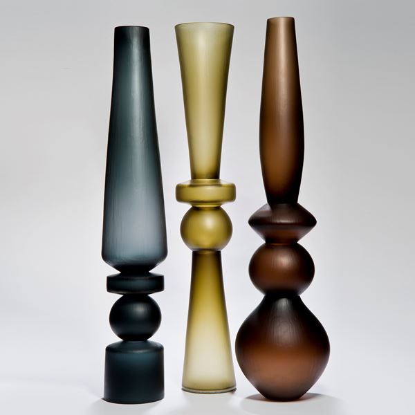 three tall art glass vases in dark blue, yellow and brown colours