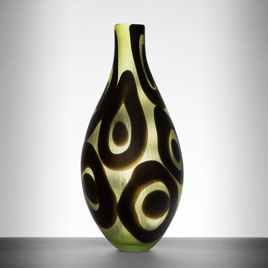modern glass art sculpted vessel with thin neck in light green with black circle pattern