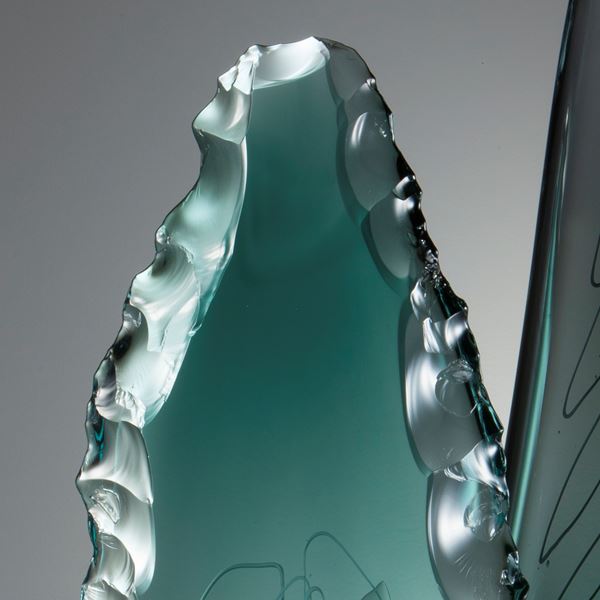 two leaf-shaped glass art sculptures in aqua and jade on clear rectangular base