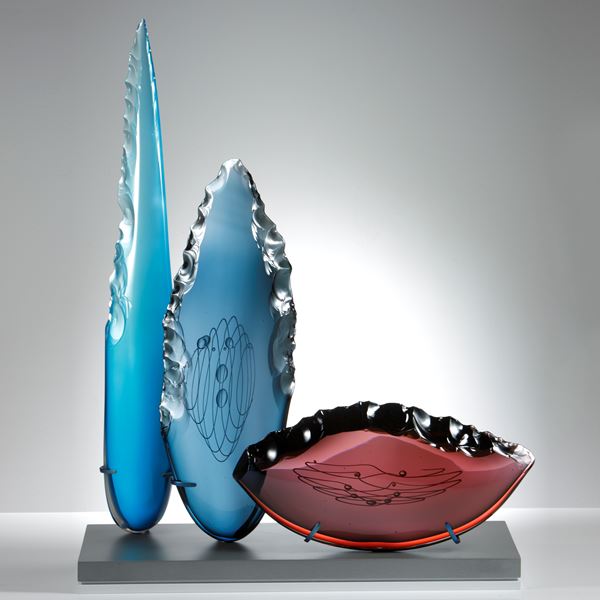 blue steel and plum glass cloves in different heights and shapes on grey glass base