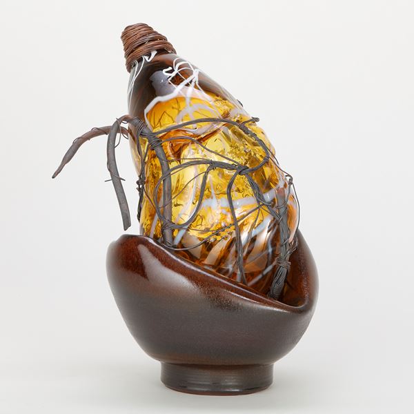 pear shaped amber glasswork art piece in basket with wire