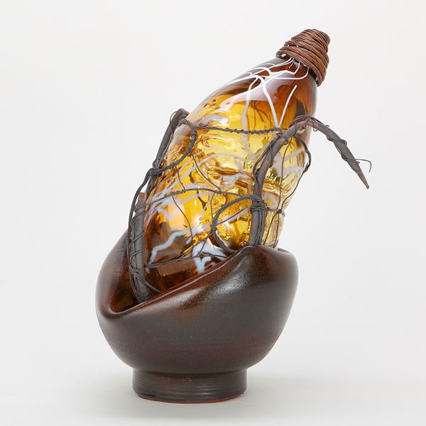 pear shaped amber glasswork art piece in basket with wire