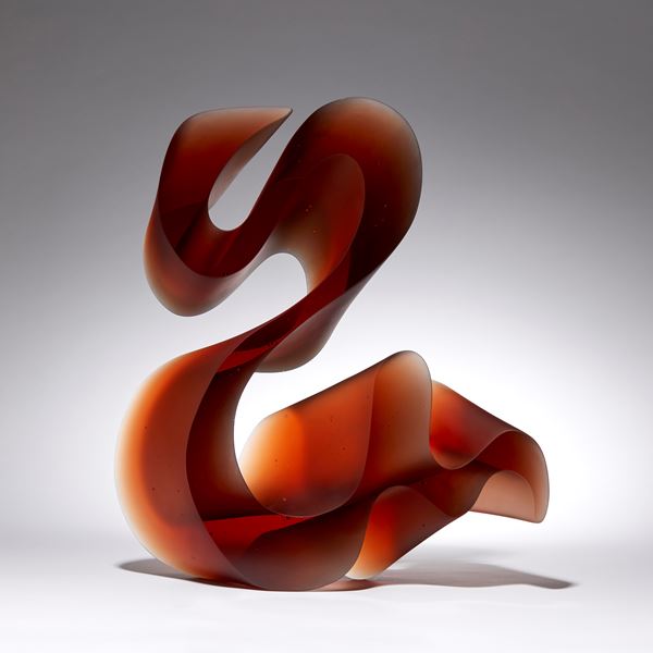 amber red fluid lined sculpture with dramatic sweeping curves made from cast glass