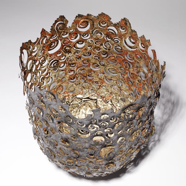dark brown and copper aged looking large metal vessel with hand cut organic ammonite swirling patter and irregular top edge