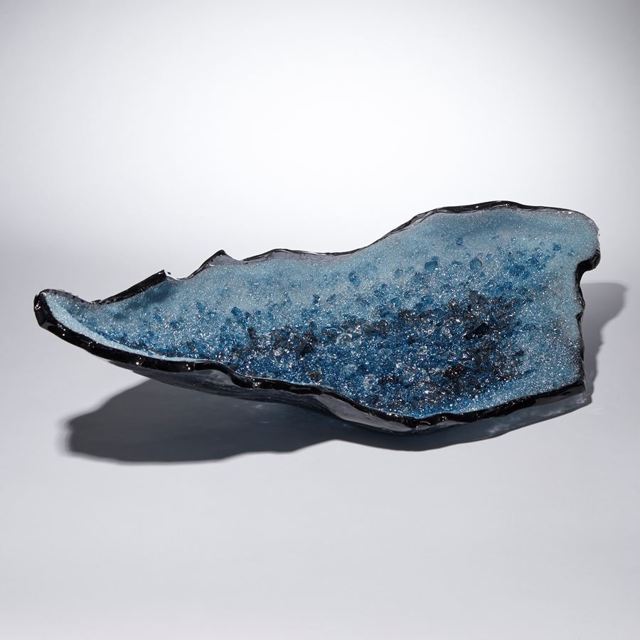 light and dark blue long organically shaped glass sculpture with a twinkling crystal covered interior