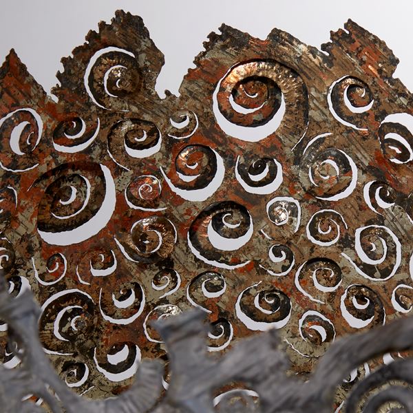 dark brown and copper aged looking large metal vessel with hand cut organic ammonite swirling patter and irregular top edge