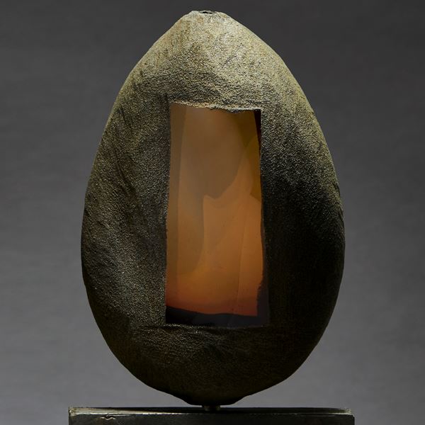 grey and brown hand made ovoid shaped glass and metal sculpture with square geometric aged metal base and rectangular orange glass window
