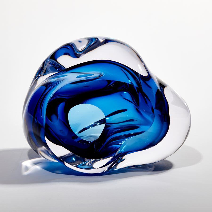 sculptural blob of handmade glass undefined in form with blue interior and clear exterior 