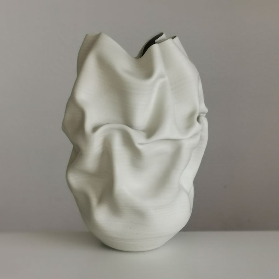 white crumpled and folded ceramic vessel with wobbly top edge handmade from clay