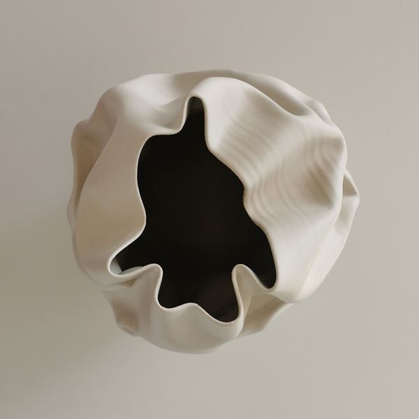 white crumpled and folded ceramic vessel with wobbly top edge handmade from clay
