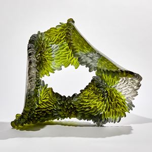 green and grey flowing squashed ring shaped textured sculpture made from cast glass