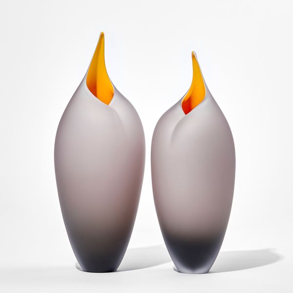 two bronze grey sleek tall rounded bird forms with pointed open beak with yellow interiors