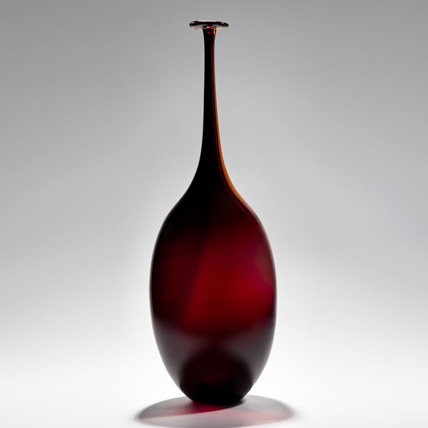 dark rich red bottle with wide body and long slim neck handblown from glass