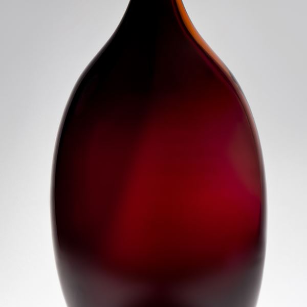 dark rich red bottle with wide body and long slim neck handblown from glass