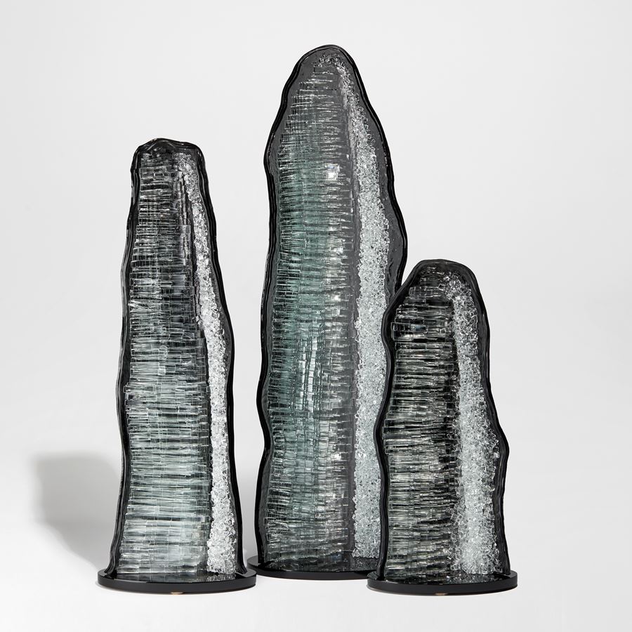 monolithic rock like handmade sculpture in  black grey and clear glass with crystal interior detail